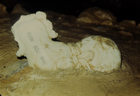 An inscribed sculpture rising from the muddy floor inside the grottoe